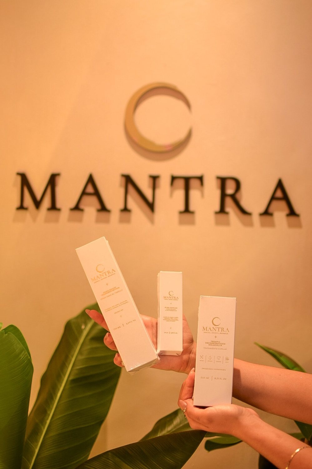 Cajas de productos Mantra frente al muro con el logo